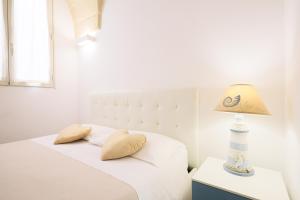 a white bedroom with a bed with a lamp on a nightstand at B&B Casa di Anita in Arnesano +83 photos
