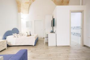 a white bedroom with a bed and a tv at B&B Casa di Anita in Arnesano