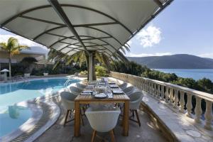 a dining table and chairs next to a swimming pool at Villa Visanty with Private Pool & Access to Beach in Aigosthena