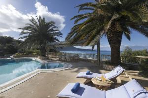 a resort with a swimming pool and a palm tree at Villa Visanty with Private Pool & Access to Beach in Aigosthena