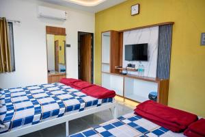 a bedroom with two beds and a tv in it at Laxman AC Lodge Jejuri - by Martandbhairav hospitality LLP in Jejūri