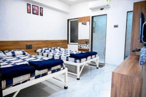 a room with three beds in a room at Laxman AC Lodge Jejuri - by Martandbhairav hospitality LLP in Jejūri