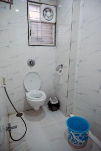 a bathroom with a toilet and a window and a bucket at Laxman AC Lodge Jejuri - by Martandbhairav hospitality LLP in Jejūri