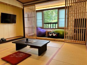 ein Wohnzimmer mit einem Tisch und einem großen Fenster in der Unterkunft 阿蘇扇温泉 おおぎ荘 in Minamioguni