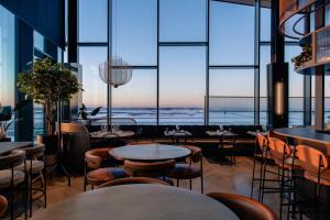 a restaurant with tables and chairs and large windows at Clarion Hotel Helsinki Airport in Vantaa