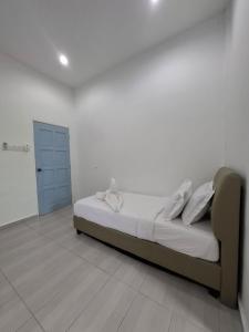 a bed in a white room with a blue door at Guesthouse Sungai Musoh in Pengerang