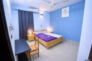 a small bedroom with a purple bed and a table at Villa Sahel in Niamey