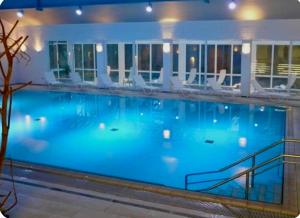 a large blue swimming pool with white chairs in a building at Luxus Chalet in Oberstaufen inkl Wellness Pool und Bergbahnen in Oberstaufen