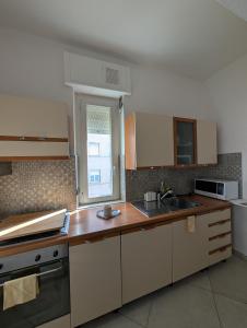 a kitchen with white cabinets and a sink and a window at Dietro l'Angolo in Millesimo