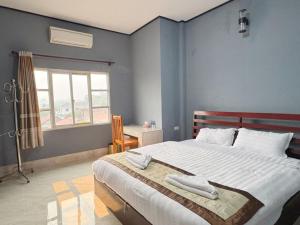 a bedroom with a large bed with two towels on it at Meesokxay Hotel Vang Vieng in Vang Vieng
