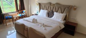 a bedroom with a large bed with towels on it at Corbett Sun Shine in Rāmnagar