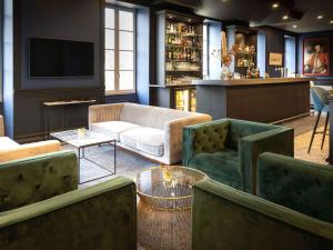 a living room with a couch and a tv at Hôtel Mercure Rochefort La Corderie Royale in Rochefort