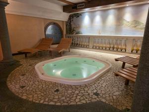 a jacuzzi tub in a room with two benches at Hotel La Pastorella in Livigno +92 photos