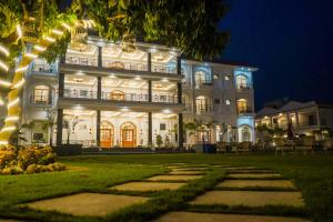 a large white house at night with lights at The Lychee Hotel & Resort by The Altruist in Rāmnagar +62 photos