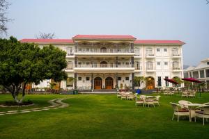 a large building with tables and chairs on a lawn at The Lychee Hotel & Resort by The Altruist in Rāmnagar