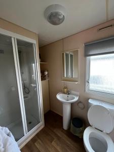 a bathroom with a shower and a toilet and a sink at California cliffs caravan in Great Yarmouth +11 photos