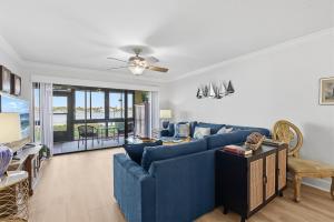 a living room with a blue couch and a ceiling fan at Bouchelle Island 102 in New Smyrna Beach