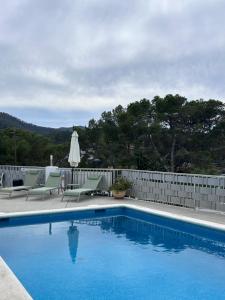 a swimming pool with two chairs and a umbrella at Apartamentos Portinatx Sea View in Portinatx