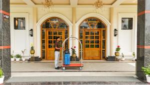 a man standing in front of a building with a luggage cart at The Lychee Hotel & Resort by The Altruist in Rāmnagar