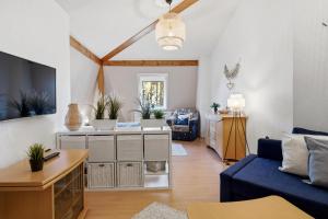 a living room with a blue couch and a tv at Haus Berlin Krabbengalerie in Loddin