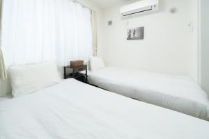 two beds in a bedroom with white sheets and a window at Laguna Verde Misono 103 in Sapporo