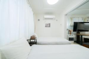 two beds in a hotel room with a television at Laguna Verde Misono 103 in Sapporo