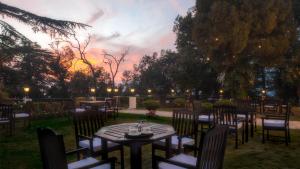 a table and chairs with a sunset in the background at The Claridges Nabha Residence in Mussoorie