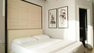 a bedroom with a white bed with two pictures on the wall at Hotel Miami II in Golem