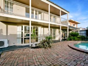 a building with a brick driveway and a swimming pool at Isle of Serenity in Frankston