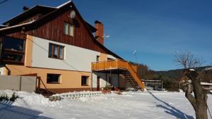 a large building with a deck in the snow at Apartmány Krásná - K68 in Jablonec nad Nisou