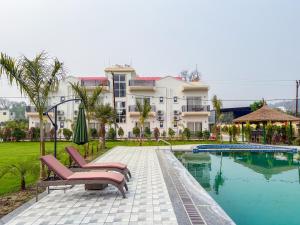 a resort with a pool and two chairs and a building at The Lychee Hotel & Resort by The Altruist in Rāmnagar