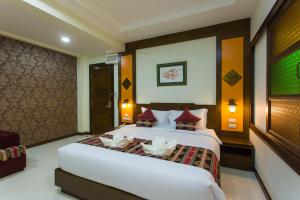 a bedroom with a large white bed with red pillows at Mhonsa Hotel in Chiang Mai