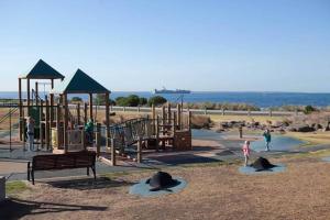a park with a playground with a slide and a bench at Williamstown Village 2 in Williamstown