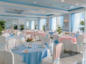 a room full of tables and chairs with white tables and flowers at Hotiday Vico Equense in Vico Equense