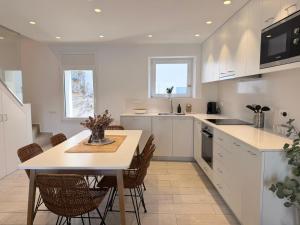 a kitchen with white cabinets and a table and chairs at POAL-Dúplex de ensueño en Cadaqués in Cadaqués +21 photos