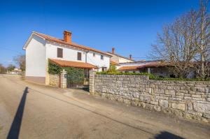a white house with a stone wall next to a street at Villa STOCK 66 by Villsy in Štokovci