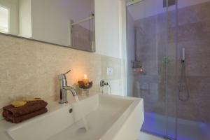 a bathroom with a sink and a shower with a candle at Elafi Penthouse in Cagliari +35 photos