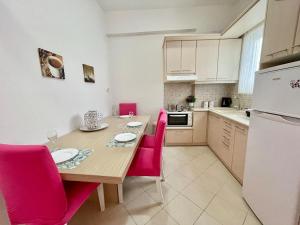 a kitchen with a wooden table and pink chairs at FLY, Oneiropagida, Aegina in Vathí +16 photos