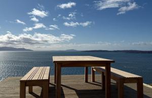 a wooden table and benches sitting on a wooden deck overlooking the water at Taigh Druim in Elgol