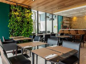 a restaurant with tables and chairs and a green wall at Mercure Belem Boulevard in Belém