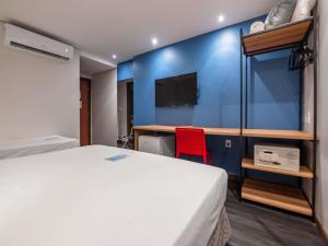 a bedroom with a bed and a desk with a tv at ibis Styles Belem Nazare in Belém