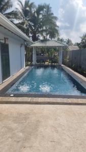 a swimming pool with an umbrella and a table at Shells By D in Negombo