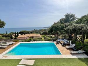 a swimming pool in a yard with lounge chairs and the ocean at Villa Horizon Bleu in Sainte-Maxime