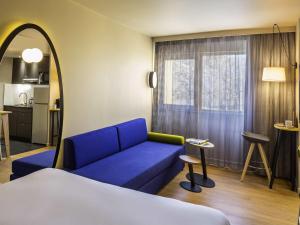 a living room with a blue couch and a kitchen at Aparthotel Adagio access Montpellier Centre in Montpellier +71 photos