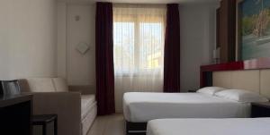 a hotel room with two beds and a window at Kairos Garda Hotel in Castelnuovo del Garda
