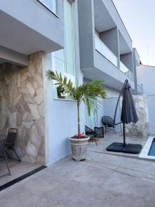 a patio with a palm tree and an umbrella at Casa beira Mar in Itanhaém