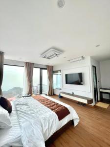 a bedroom with a large bed and a flat screen tv at Time Villa in Tam Ðảo