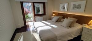 a bedroom with a large white bed with a window at Casa El Castañal con Piscina Privada in Vigo +68 photos