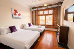 two beds in a small room with a window at Aura Hotel in Wellington
