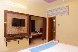a bedroom with a bed and a tv on a wall at Bhavan Resorts in Yercaud